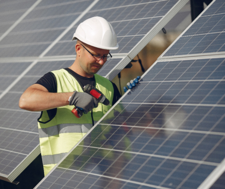 Man in a white helmet near a solar panel