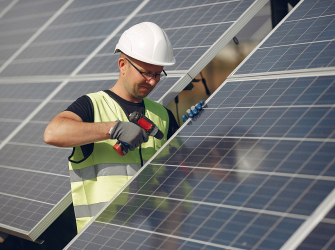 Man in a white helmet near a solar panel